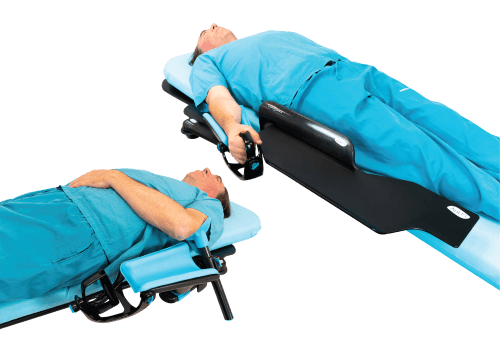 A man in scrubs on a medical table demonstrating two different arm positioning systems: one with an elevated arm support and handgrip, another with an armrest.