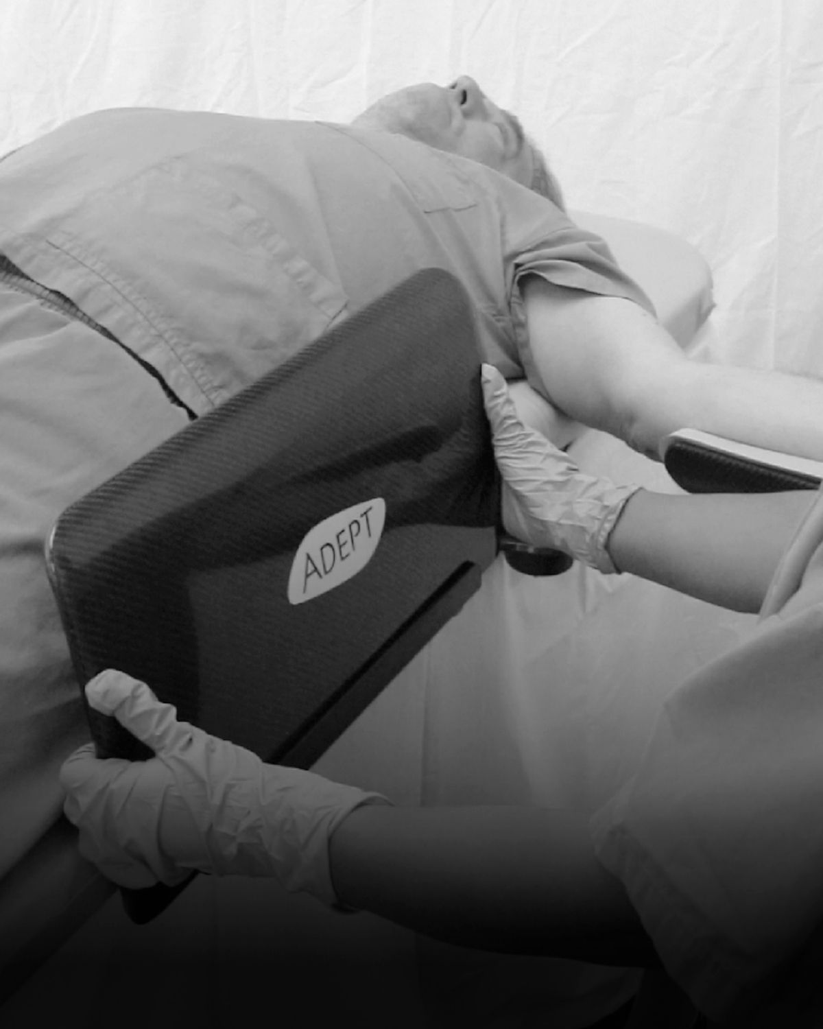 A medical professional positions an "ADEPT" device near a patient's arm.