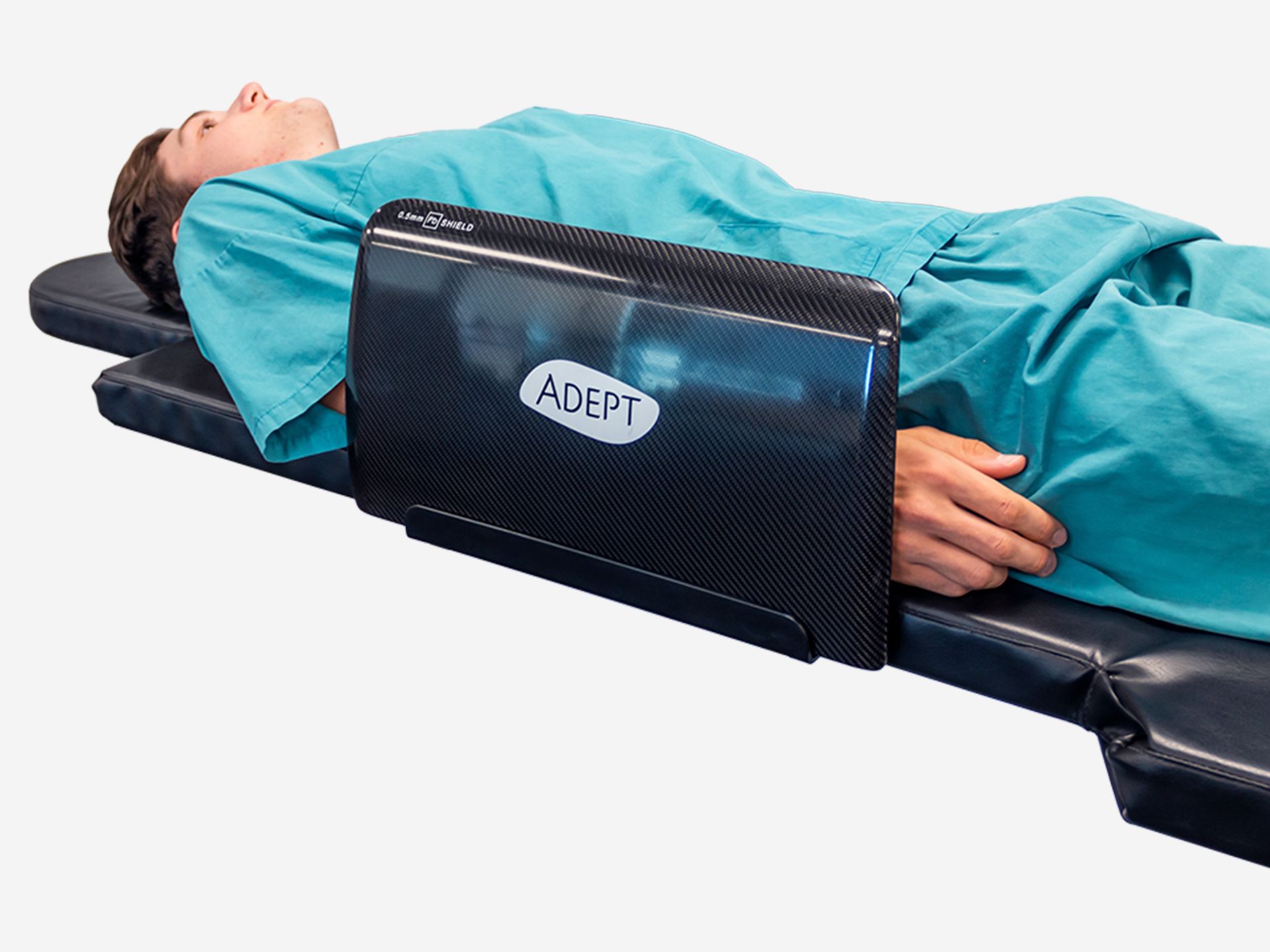 A patient lies on a medical table with a dark "ADEPT X-ray SHIELD" covering their left arm and torso.
