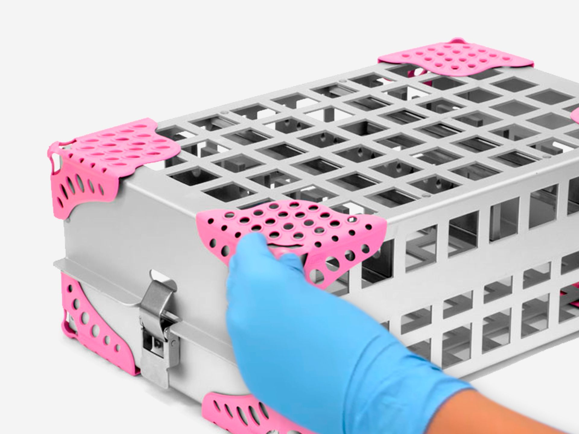 A gloved hand applying a pink corner protector to a silver medical sterilization container.