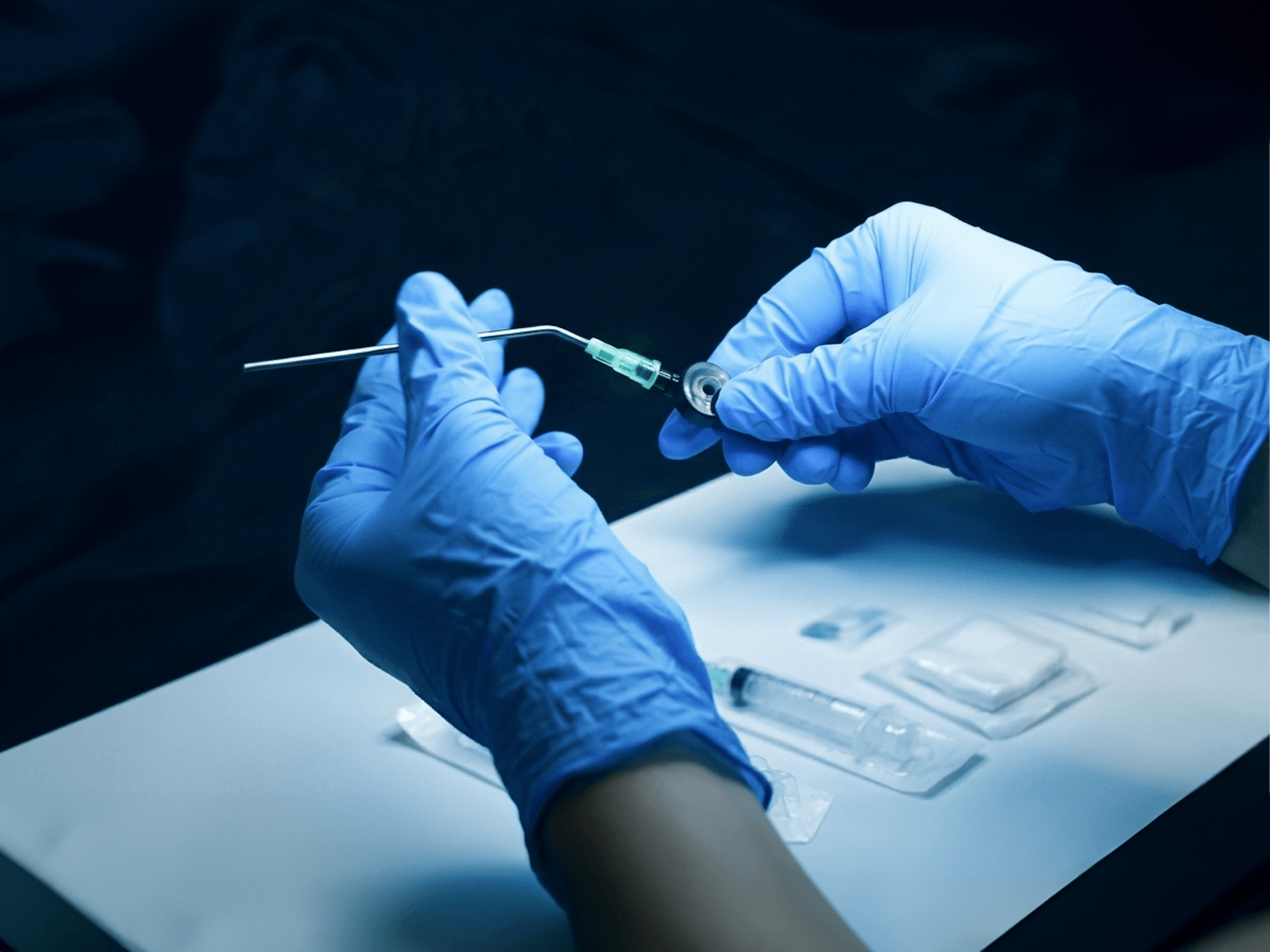 Gloved hands preparing a syringe and medical vial.