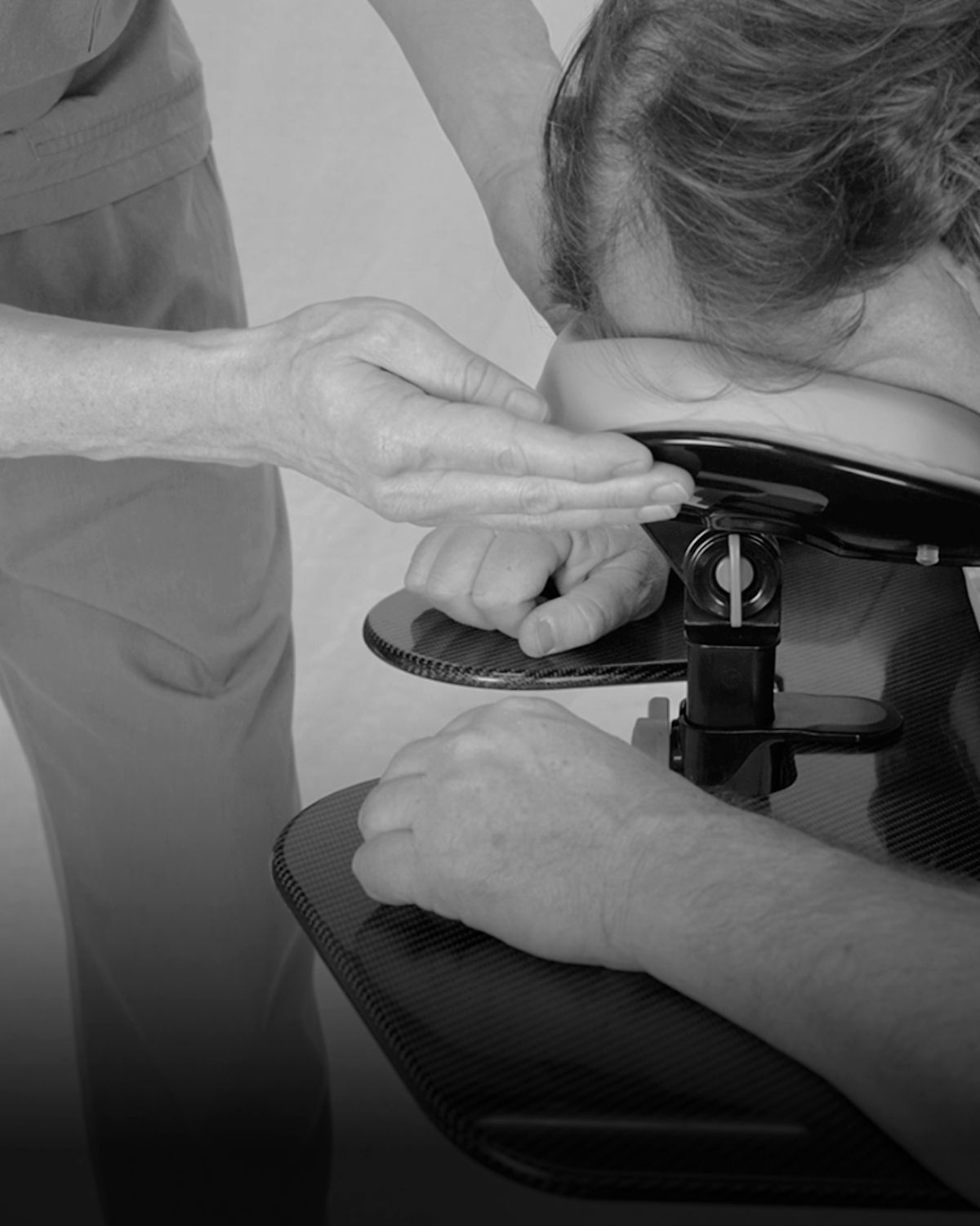 Black and white photo of a person receiving a neck and shoulder massage on a portable chair.