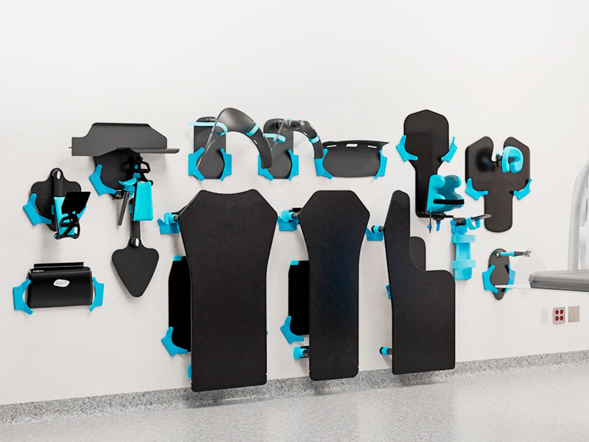Black medical patient positioning accessories with blue mounting hardware displayed on a white wall.